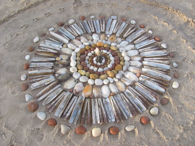 A beach mandala by Therese Muskus made from stones and shells