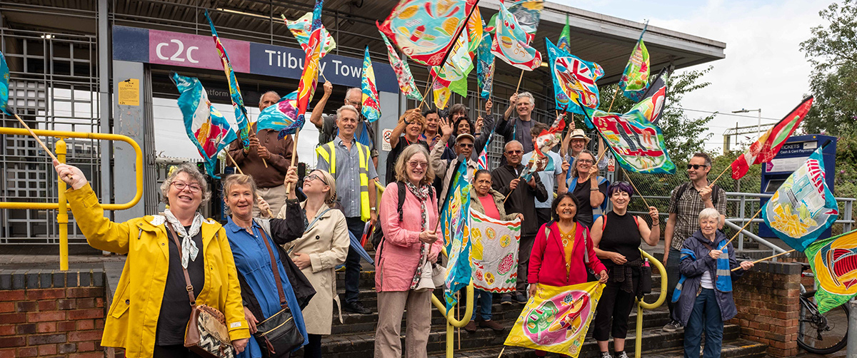 A group of people waving flags outside Tilbury station