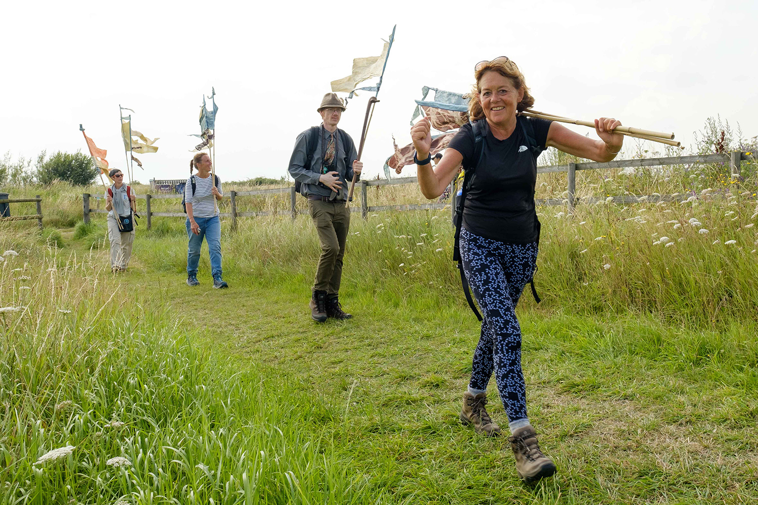 Walkers stride towards the viewer carrying pennant shaped flags