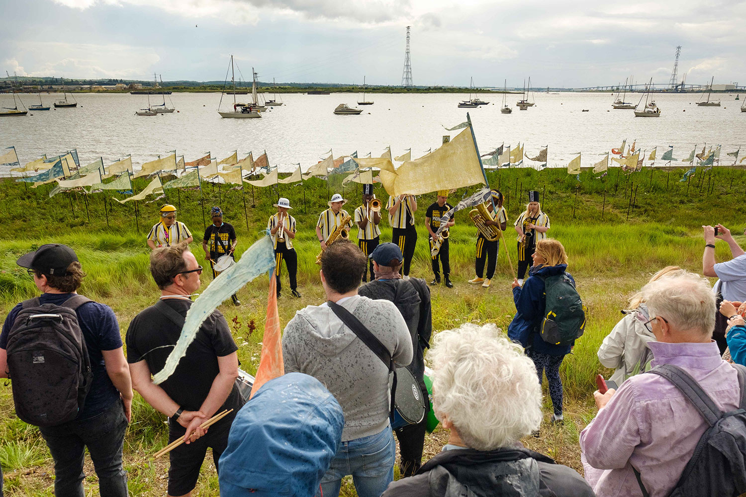 A crowd enjoys a performance by Kinetika Bloco on the banks of the Thames surrounded by Beach of Dreams pennants