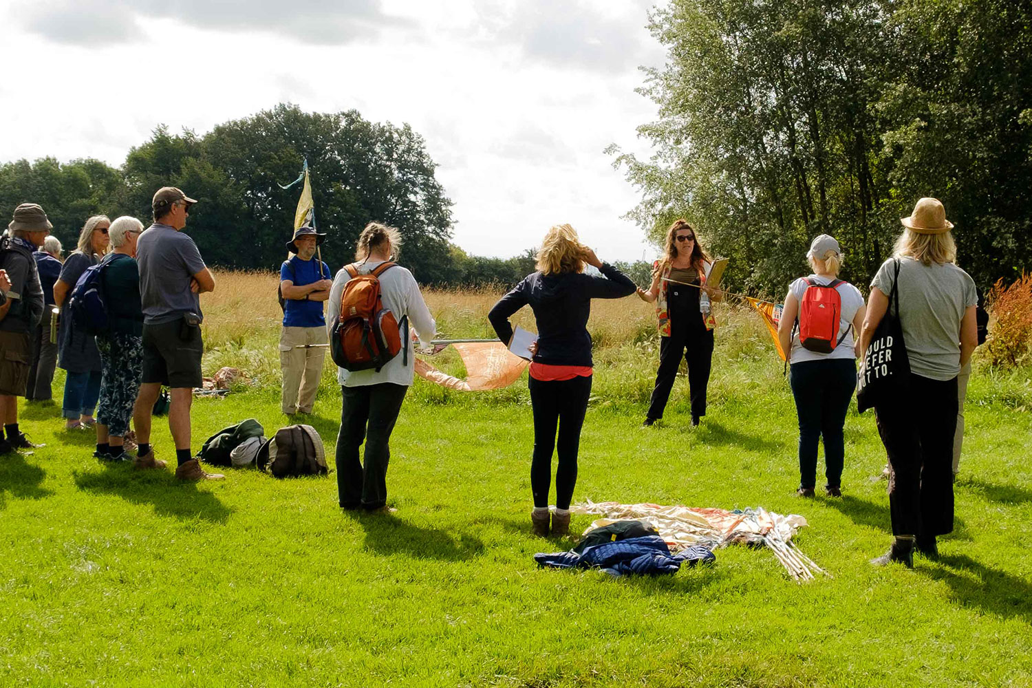 Katie Beadle talks to a circle of walkers stood on grass with trees in the background