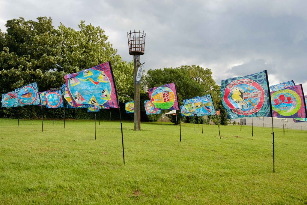 Flags illustrating aspects of the area decorate the grass in front of the Purfleet-on-Thames Beacon