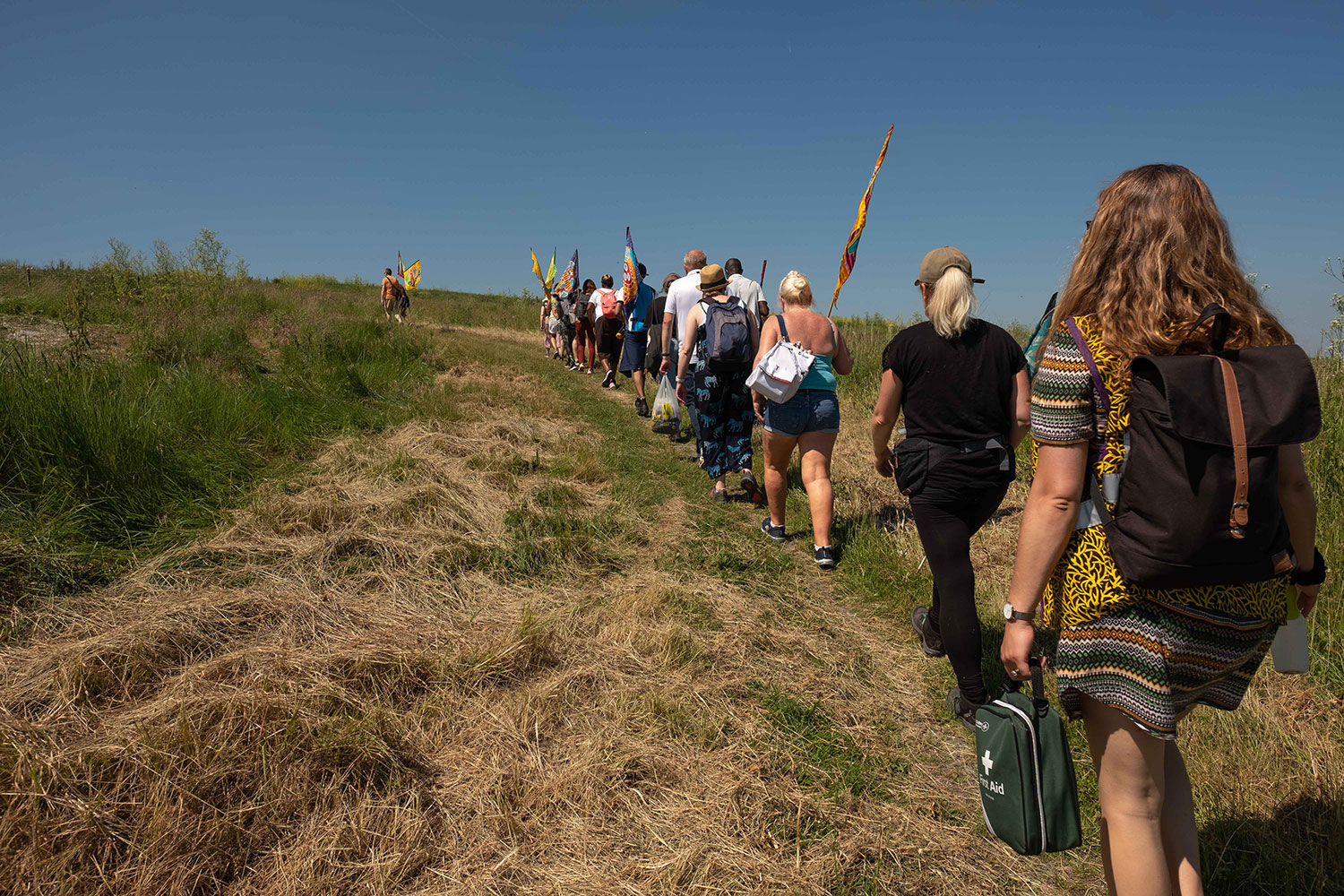 A line of walkers stretches into the distance over the dry grass of Rainham marshes